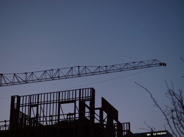 Photo of construction crane and building framework at dusk.
