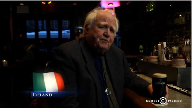 {Image: an older white man sits at a bar with a full glass of dark beer in a Guinness glass; image of the Italian flag (three horizontal green, white and orange stripes) and the word "Ireland" in the lower lefthand corner.}
