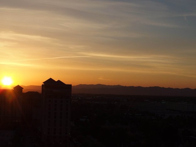 {Image:  orange sunrise with the silhouette of a building in the lower left-hand corner of the photo.}