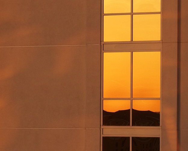 {Image:  mountains and sunrise reflected in the windows of a highrise building.}