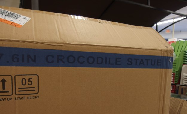 {Image: : Cardboard packing box with the words "crocodile statue" on the outside.}