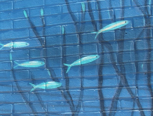 {Image:  close up of part of the mural showing a five small teal-colored fish.}