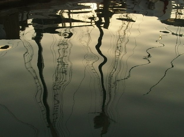 Image:  reflection of sailboat masts in the water. 