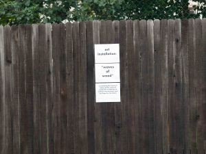 Image: wooden fence with a sign consisting of three pieces of white paper stapled to it.