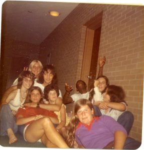 Image:  group photo in a dorm hallway, including 7 white girls ranging in age from 12 to 20, a 20-30 year old man (Dr. John), and a black teen-ager.  