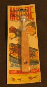 Image:  tool with very small scoop at the end; packaging is in Spanish.  