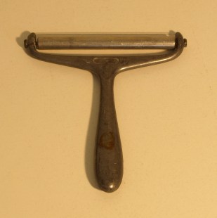 Image: old cheese parer with handle and single blade.