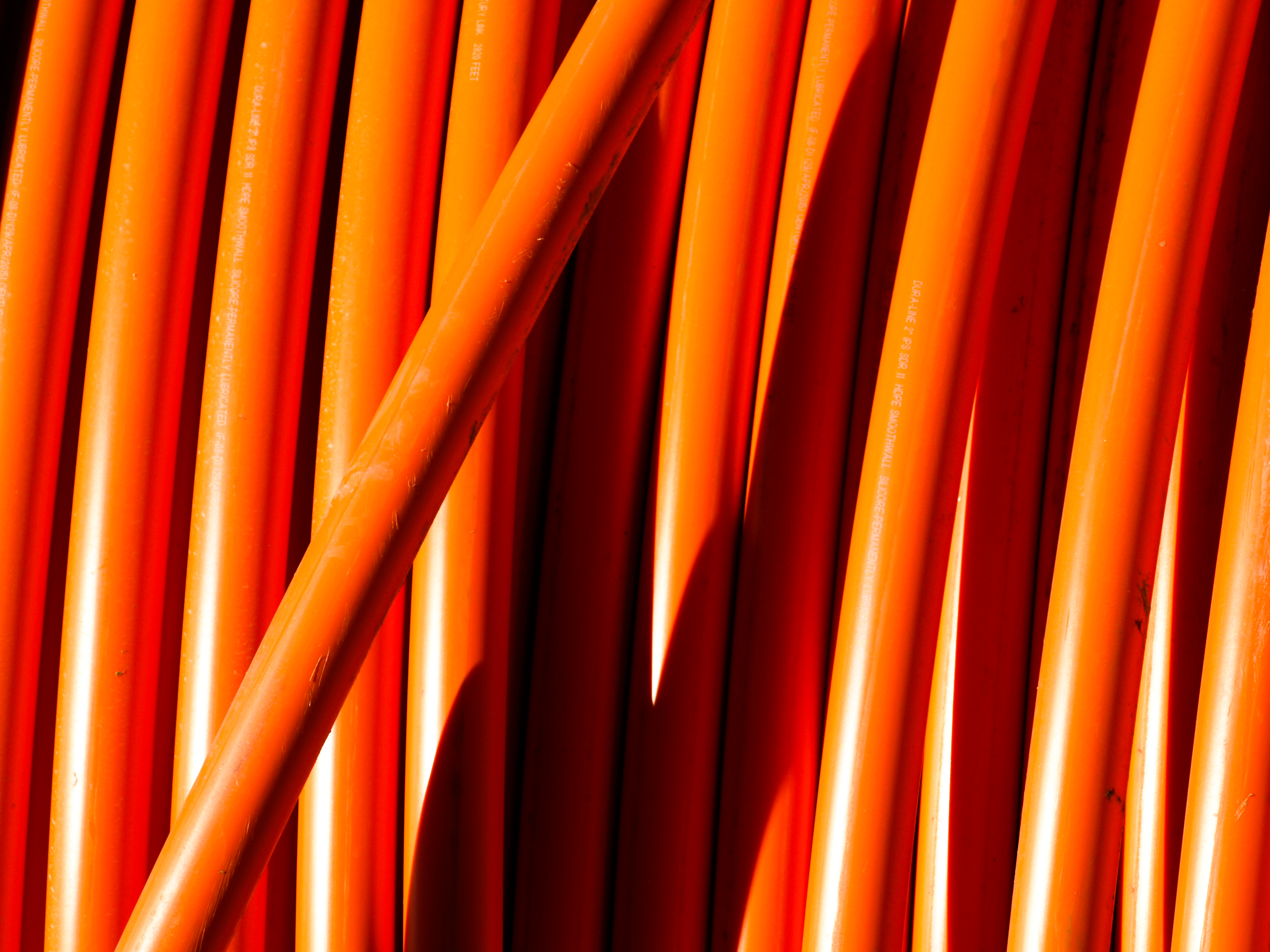 Image:  Close up of bright orange piping arrayed vertically in the photo. 
