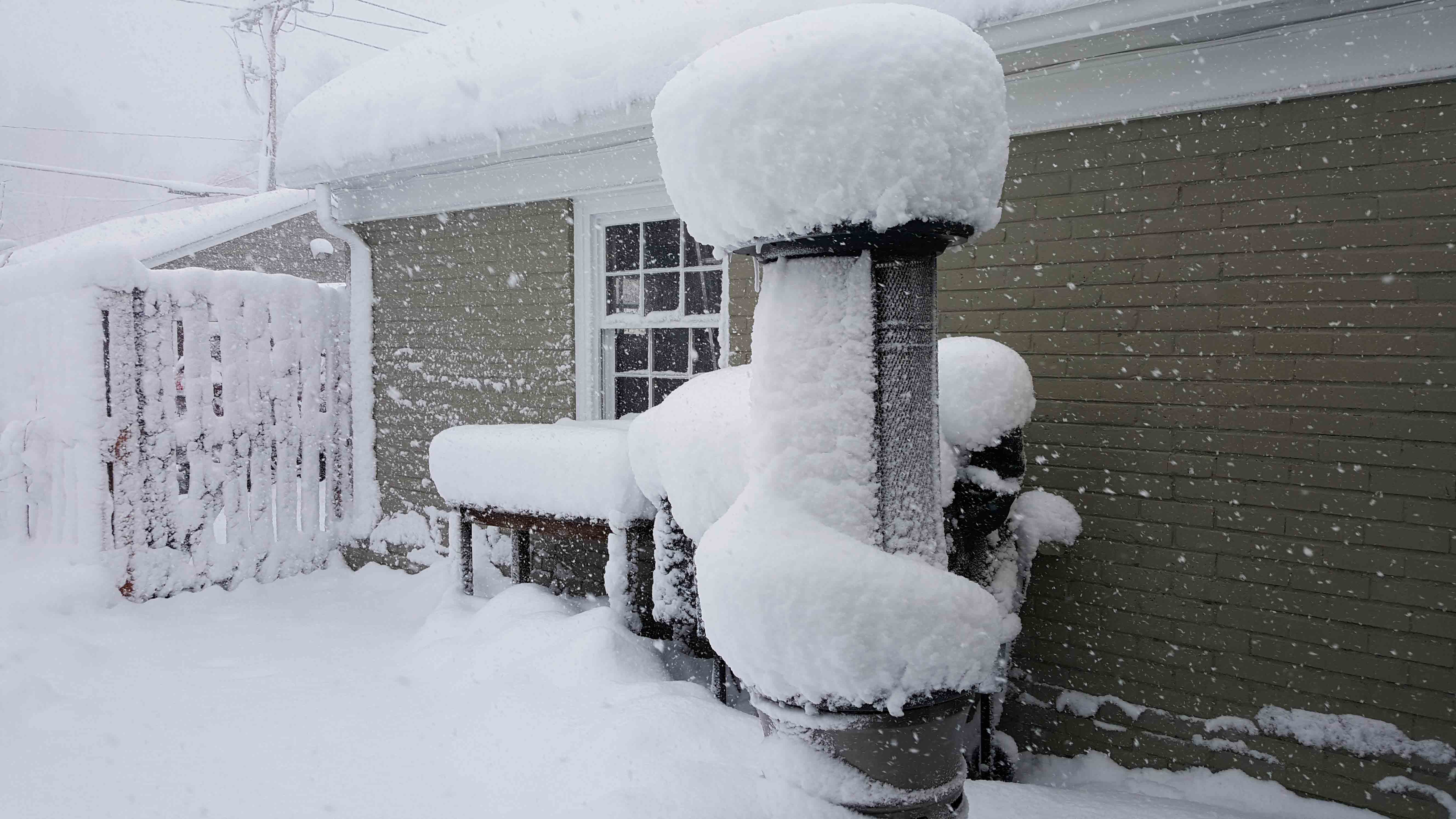 Image: Tall propane heater on a back patio with a large pouf of snow on top. 