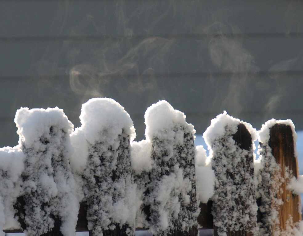 Image: four pickets of a fence with patchy snow and steam rising.